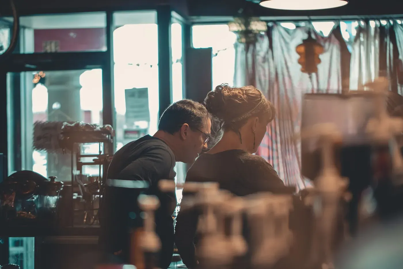 Two people working behind the counter of a small café.