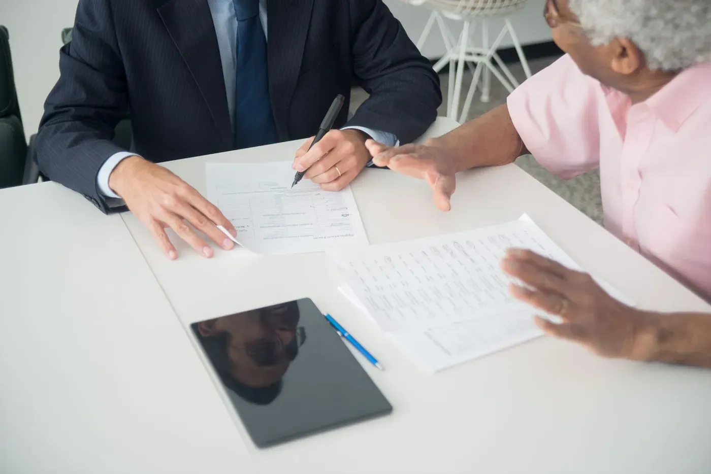 A consultant and a client going through printed documents at an office table.