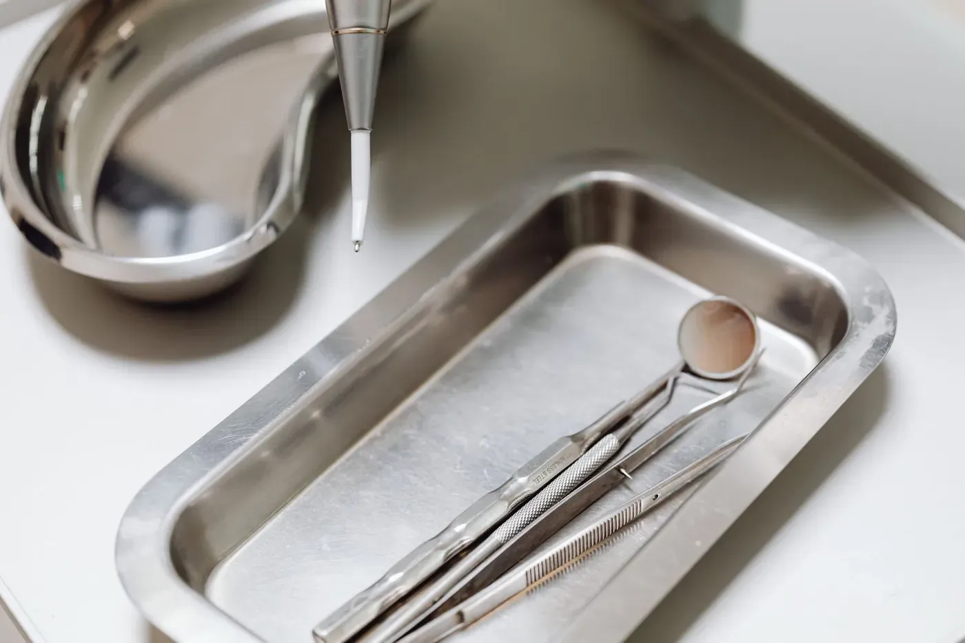 Dental instruments and a mouth mirror lying in a steel tray.