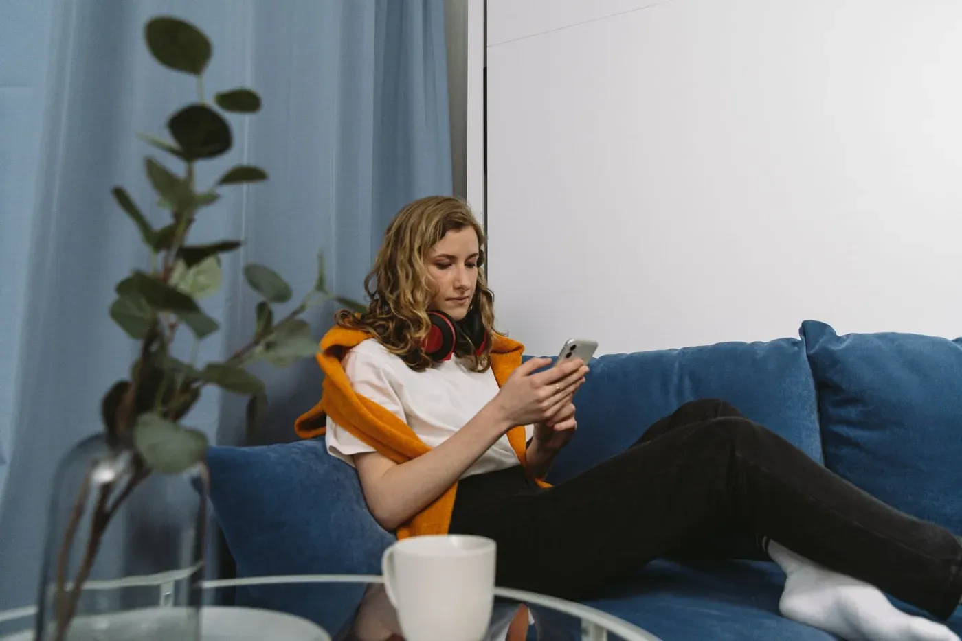 A woman sitting on a blue sofa looking at her phone.