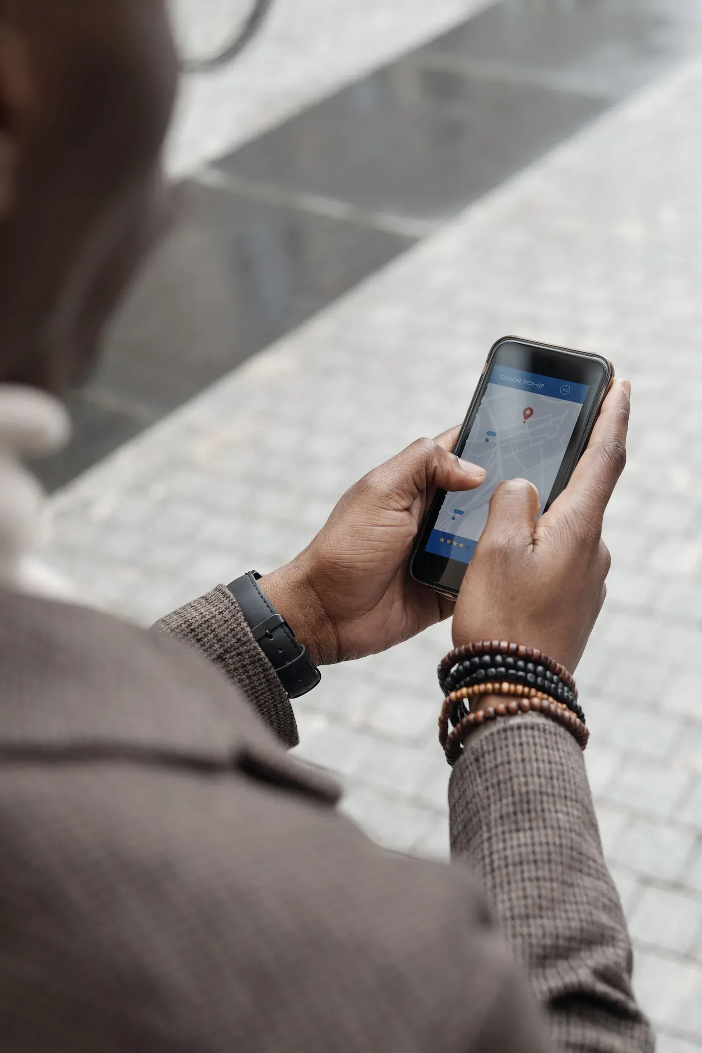 A man checking a map app on his phone while standing on a city pavement.
