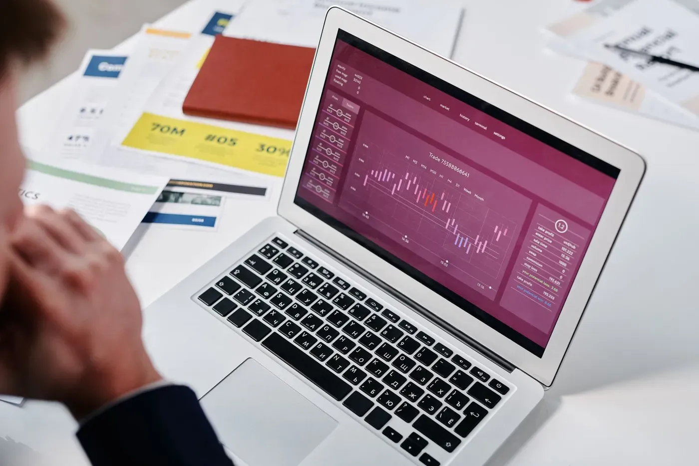 A person reviewing a performance dashboard on a laptop beside printed reports.