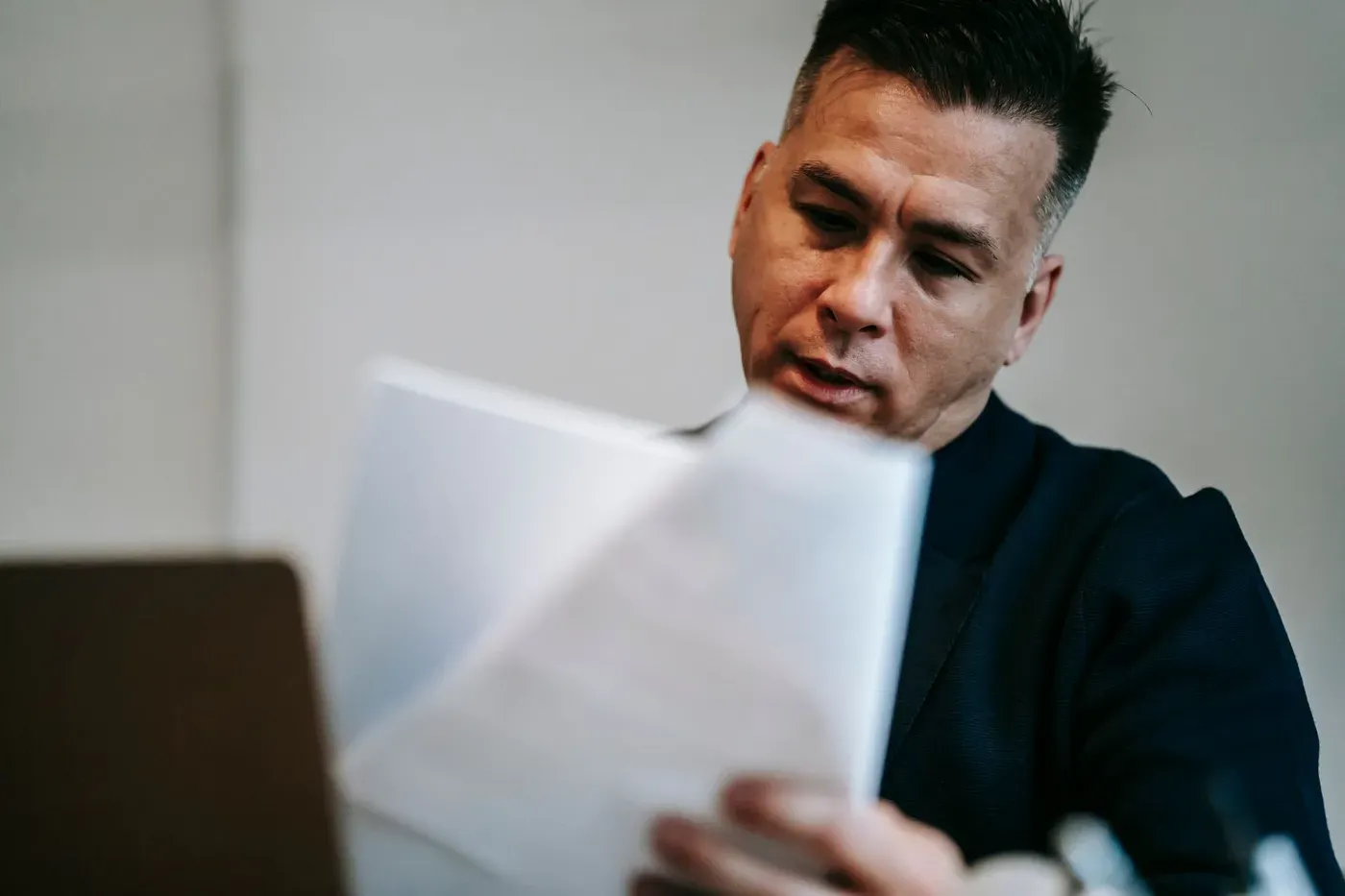 A man in an office reading through printed documents at his desk.